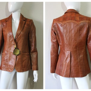 Op de afbeelding: Een bruin leren blazer met een patch-ontwerp op de rug. De blazer heeft een enkele knoopsluiting en twee zakken aan de voorkant.