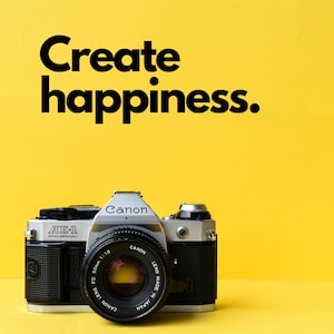 May include: A black and silver Canon AE-1 Program film camera with a 50mm lens. The camera is sitting on a yellow surface. The text "Create happiness." is written in black letters above the camera.