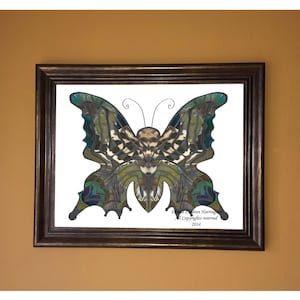May include: A framed print of a butterfly made from colorful feathers. The butterfly is green, blue, and brown with a white background. The print is signed "Daniel Leon Harrington" and dated "2014".