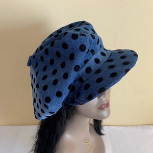 May include: A blue denim hat with black polka dots. The hat has a rounded crown and a short, curved brim. The hat is a stylish accessory.