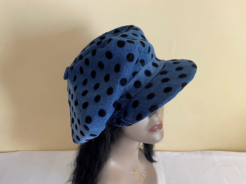 May include: A blue denim hat with black polka dots. The hat has a rounded crown and a short, curved brim. The hat is a stylish accessory.