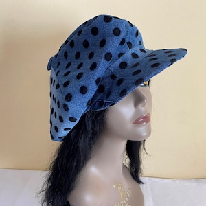 May include: Denim newsboy cap with a blue background and black polka dots. The cap has a rounded crown and a short, stiff brim. A stylish accessory for casual wear.