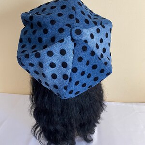 May include: A blue hat with black polka dots. The hat is made of a soft fabric and has a unique, geometric shape. The hat is a stylish accessory.