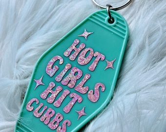 May include: A teal blue motel key chain with the text "HOT GIRLS HIT CURBS" in pink glitter lettering.