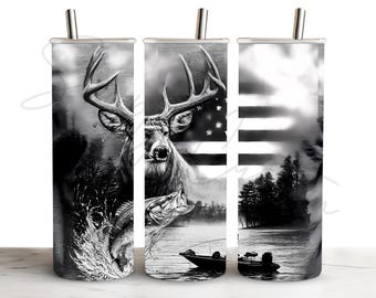 May include: A cylindrical tumbler with a straw featuring a black and white graphic design of a deer, a jumping fish, a fishing boat on water, and a stylized American flag background. The artwork wraps around the entire surface of the cup.