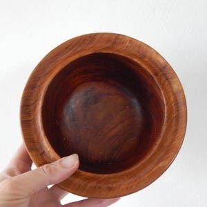 Puede incluir: Un cuenco de madera con un acabado marr&oacute;n oscuro. El cuenco es redondo y tiene una superficie lisa y pulida.
