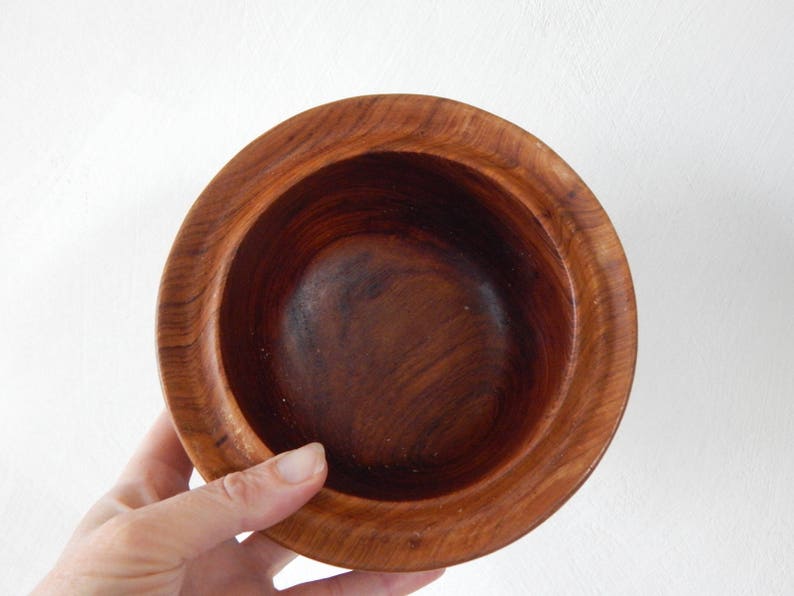 Puede incluir: Un cuenco de madera con un acabado marr&oacute;n oscuro. El cuenco es redondo y tiene una superficie lisa y pulida.