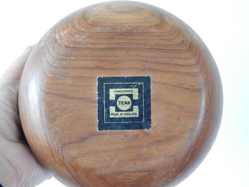 Puede incluir: Un taz&oacute;n grande, redondo y de madera hecho de teca. El taz&oacute;n est&aacute; tallado a mano y tiene una etiqueta que dice "Handcarved Teak Made in Thailand".