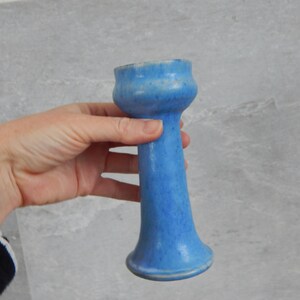 May include: A light blue ceramic vase with a flared top and a narrow base.