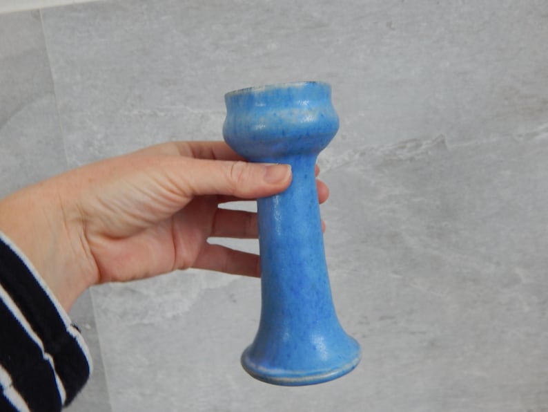 May include: A light blue ceramic vase with a flared top and a narrow base.