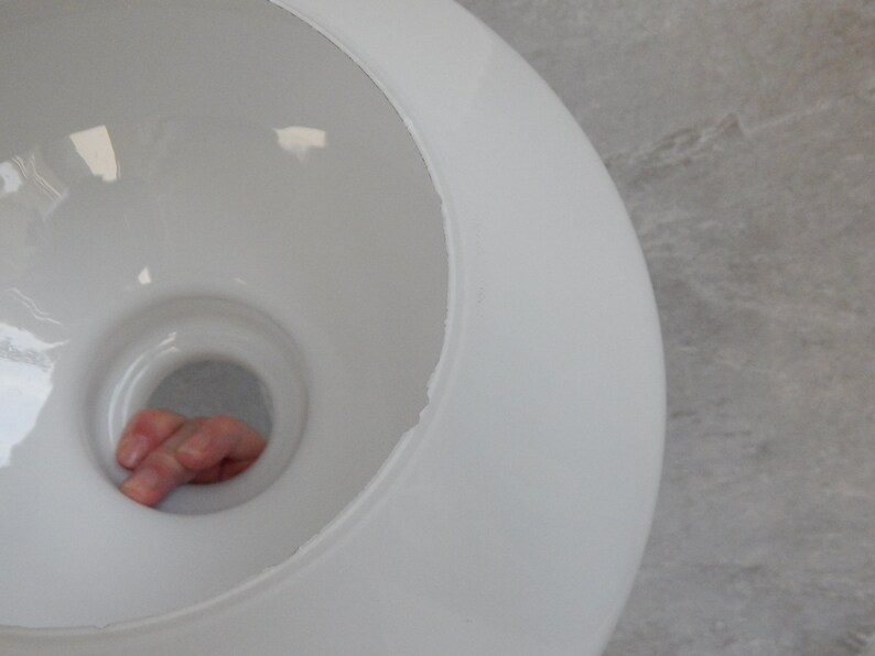 May include: White ceramic lampshade with a round opening at the top. The opening is large enough for a hand to fit through.