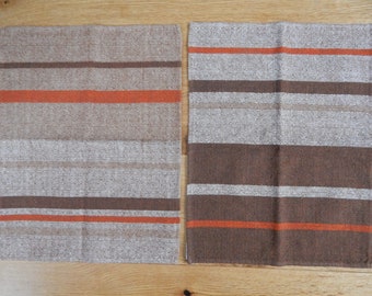 May include: Two woven placemats with a striped pattern in shades of brown, orange, and beige.