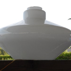 May include: A white glass lampshade shaped like a flying saucer. The lampshade is smooth and has a glossy finish.