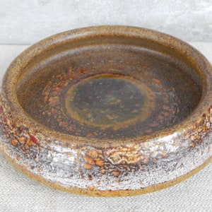 May include: A brown ceramic bowl with a textured, speckled glaze. The bowl has a wide rim and a deep, round interior.