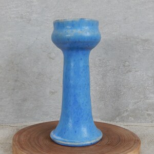 May include: A tall, light blue ceramic vase with a flared top and a wide base. The vase has a speckled glaze.
