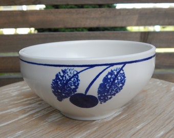 May include: A white ceramic bowl with a blue and white cherry design. The bowl is round and has a slight lip.