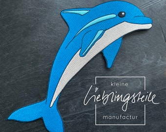 Peut inclure: Un patch brodé en forme de dauphin bleu avec un ventre blanc. Le patch est de la société "kleine lieblingsteile manufactur".