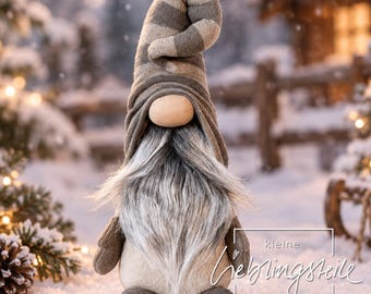 May include: A plush gnome figurine featuring a tall, floppy, brown and beige striped hat, a smooth beige nose, and a long, shaggy gray and white faux fur beard. The gnome has brown fabric arms and feet, with text reading kleine lieblingsteile manufactur.