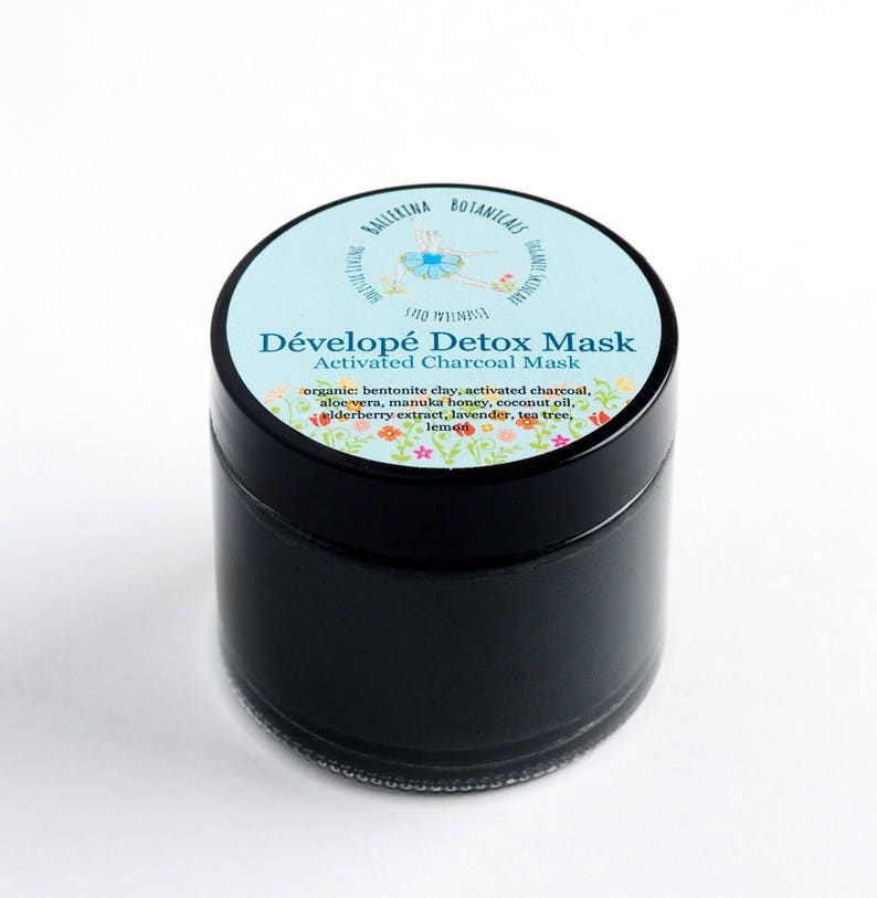 May include: A black jar with a blue and white label that says "D&eacute;velop&eacute; Detox Mask Activated Charcoal Mask". The label also lists the ingredients: bentonite clay, activated charcoal, aloe vera, manuka honey, coconut oil, elderberry extract, lavender, tea tree, and lemon.