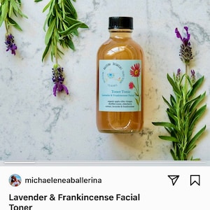 May include: A clear glass bottle with a brown liquid inside. The bottle is labeled "Toner Tonic Lavender & Frankincense Facial Toner" and lists the ingredients as organic apple cider vinegar, distilled water, elderberry extract, lavender & frankincense. The bottle is surrounded by lavender flowers and green leaves.