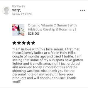 May include: A glass bottle of organic vitamin C serum with a dropper. The bottle is labeled with the product name and ingredients, including hibiscus, rosehip, and rosemary. The product is priced at $28.00.