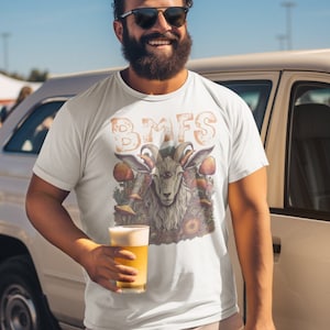 May include: A white t-shirt with a graphic of a one-eyed goat with horns and mushrooms. The text "BMFS" is printed above the goat. A person is wearing the shirt and holding a glass of beer.