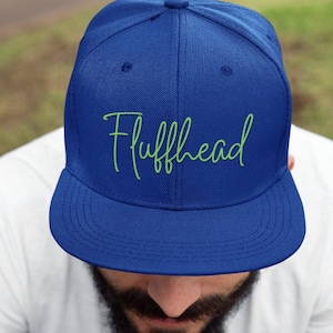 May include: A blue baseball cap with a green embroidered logo that says "Fluffhead".