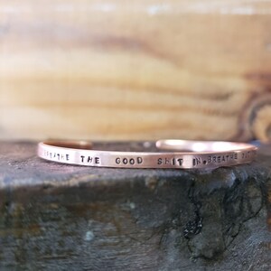 May include: A copper bracelet with the inscription "Breathe the good shit in, breathe out the bad."