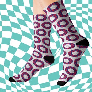 May include: Socks featuring a white base with a repeating pattern of red and blue donut shapes. The heels and toes are black. The background is a distorted checkerboard pattern in white and teal.