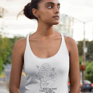 May include: White tank top with a black line drawing of a woman's face with a rose and clouds. The text "Take my hand, I know a place..." is printed below the drawing.