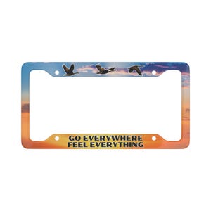 May include: A license plate frame with a sunset background and three flying geese. The text "GO EVERYWHERE FEEL EVERYTHING" is printed on the frame.