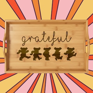 Op de afbeelding: Een rechthoekig bamboe serveerblad met handvatten. Het woord "grateful" is in cursief geschreven. Daaronder staan vijf dansende berensilhouetten. De achtergrond heeft een retro ontwerp in oranje, roze en geel.