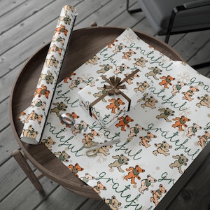 May include: A roll of wrapping paper, a wrapped gift, and a sheet of wrapping paper with a repeating pattern of cartoon bears in orange, brown, and tan. The word "grateful" is written in green cursive.