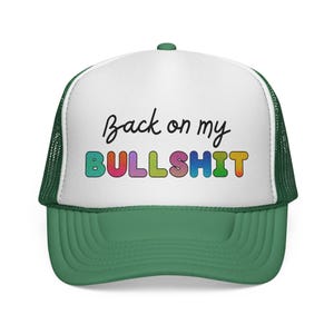 Könnte beinhalten: Grün-weiße Trucker-Cap mit dem Schriftzug "Back on my BULLSHIT" in schwarzer Schrift und bunten Buchstaben. Die Cap hat einen grünen Schirm und ein Mesh-Rückenteil.