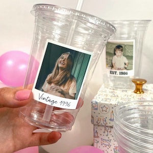 May include: A clear plastic tumbler with a lid and straw, featuring a square photo print of a smiling person and the text "Vintage 1996" printed in black script at the bottom of the image. The cup is transparent and holds a custom photograph.