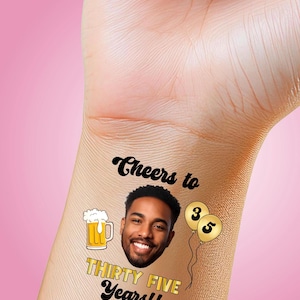 May include: Temporary tattoo with a smiling man's face, a beer mug, and gold balloons with the numbers 3 and 5. The tattoo also includes the text "Cheers to Thirty Five Years!!" in black and gold.