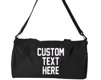 May include: Black duffel bag with a white adjustable shoulder strap. The bag has the text "CUSTOM TEXT HERE" printed on the front.