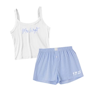 Peut inclure: Un ensemble de détente composé d'un caraco blanc avec l'inscription "Mrs. Wright" en bleu clair. Il est accompagné d'un short de boxer à rayures bleu clair et blanc, avec la date "9.19.25" en blanc. Idéal pour se détendre.