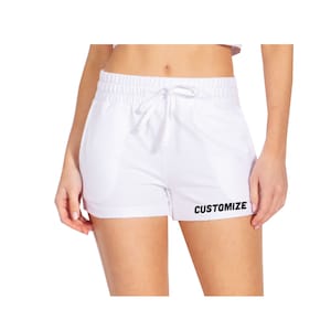 May include: White athletic shorts with a drawstring waist and the word "CUSTOMIZE" printed on the right leg.