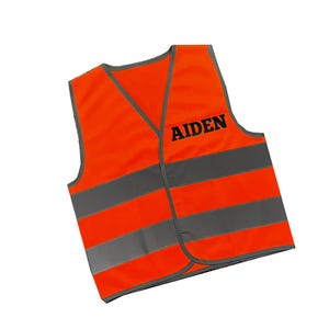 Könnte beinhalten: Orangefarbene und graue Sicherheitsweste mit reflektierenden Streifen und dem Namen "AIDEN" in Schwarz bedruckt.