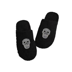 May include: A pair of black fuzzy slippers with a gray skull design embroidered on each slipper.