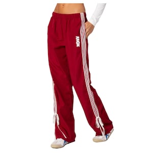 May include: Red track pants with white stripes down the sides and the word "ANGIE" printed on the right leg.