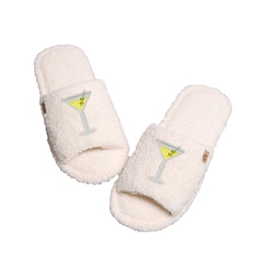 May include: Pair of white fuzzy slippers with a martini glass design. The slippers have a closed toe and an open heel.