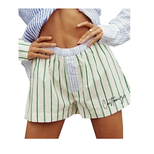 May include: White and green striped pajama shorts with a blue button fly and the word "Customize" written in black on the right leg.