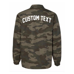 May include: A green, brown, and black camouflage jacket with a white "CUSTOM TEXT" on the back.