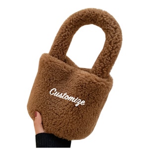 May include: A brown faux fur bucket bag with a top handle. The bag has the word "Customize" embroidered on the front.