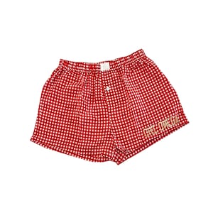 Könnte beinhalten: Rote und weiße Gingham-Boxershorts mit dem Schriftzug "CHI OMEGA" in Gold auf der Seite gestickt.