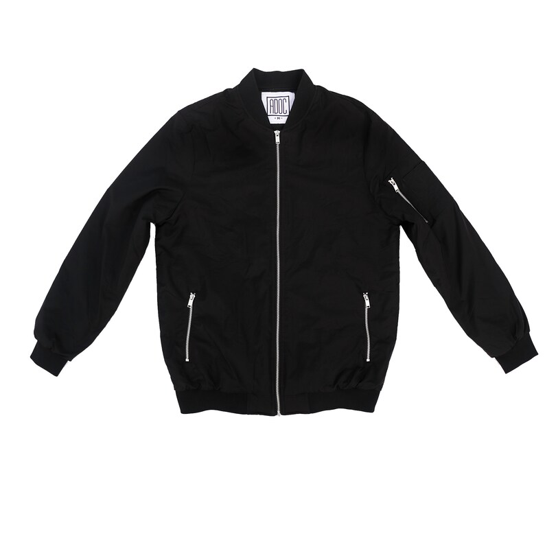 May include: A black bomber jacket with a zipper closure and two zippered pockets on the sleeves. The jacket has a ribbed collar and cuffs. The label on the jacket reads "ADOC".