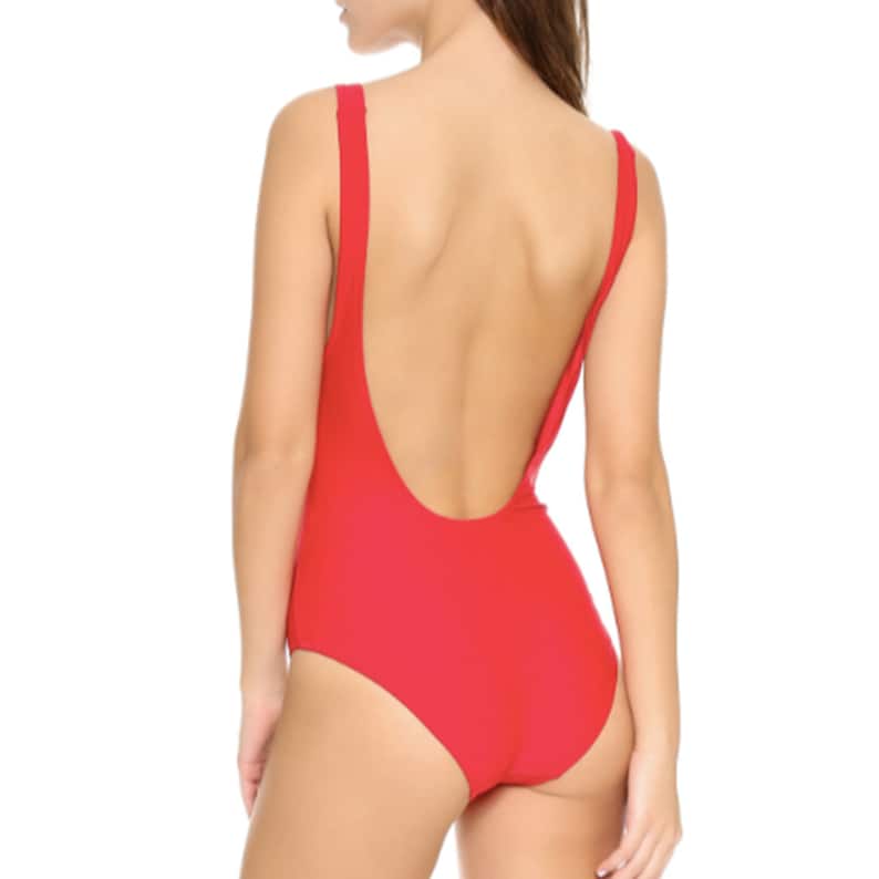 May include: A red one-piece swimsuit with a low back and a scoop neck.
