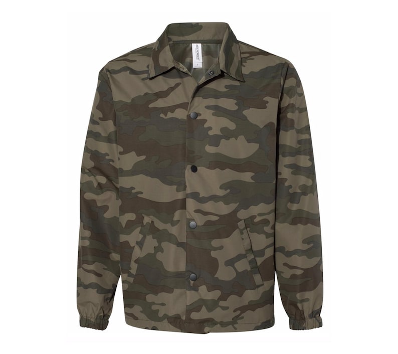 May include: A green, brown, and black camouflage print jacket with a button-up front and a pocket on the left side.